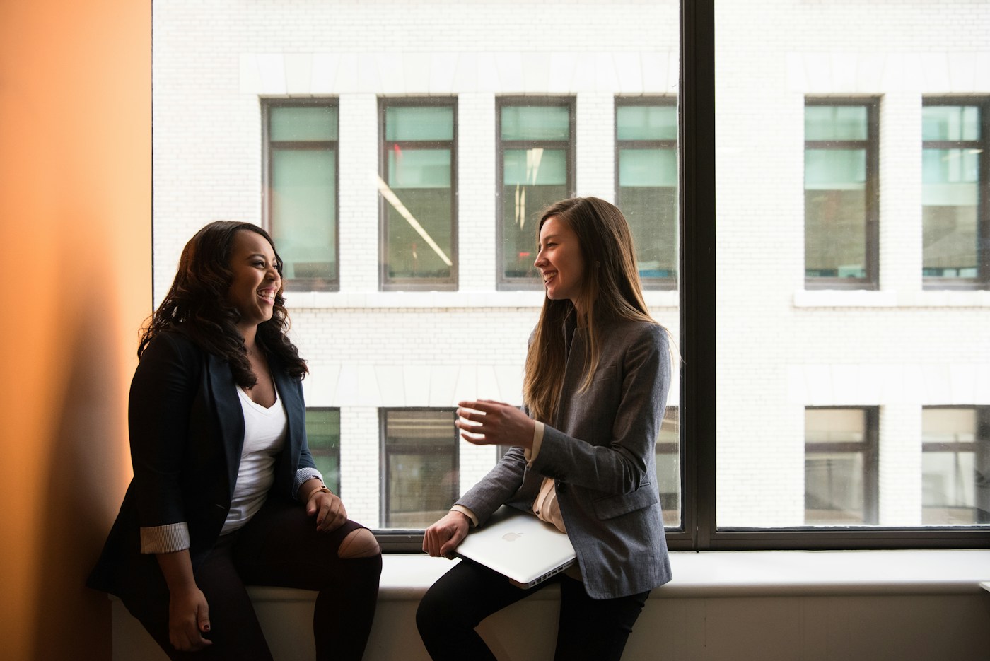 Two women sharing a conversation beside a window